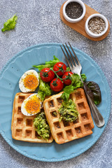 Waffles with vegetables, lettuce and egg on the kitchen table. Breakfast time. Top view.