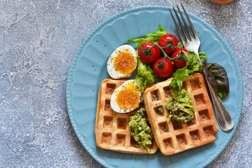 Waffles with vegetables, lettuce and egg on the kitchen table. Breakfast time. Top view.