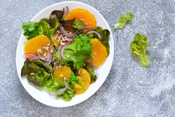 Detox nutrition. Salad with orange, onion and seeds on the kitchen table. View from above.