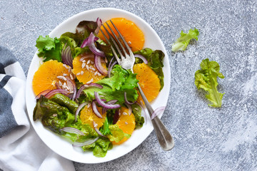 Detox nutrition. Salad with orange, onion and seeds on the kitchen table. View from above.