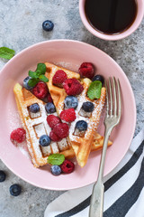 Vanilla waffles with berry in a plate for breakfast on the kitchen table. Breakfast time. Top view.