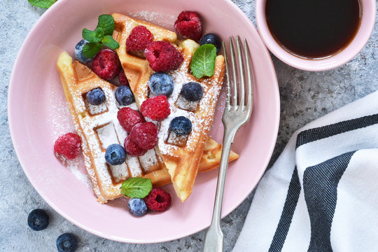 Vanilla waffles with berry in a plate for breakfast on the kitchen table. Breakfast time. Top view.