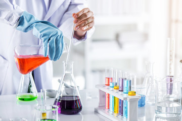 Scientist holding sampling oil or chemical liquid in flask with lab glassware in laboratory...
