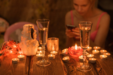 A table with glasses by candlelight and a lonely waiting woman.