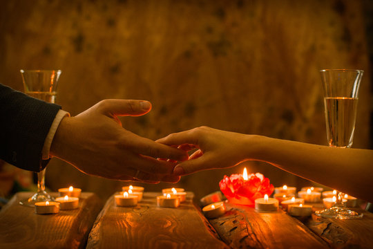 A man and a woman at a romantic dinner. The hand of a man and a woman reach for each other by candlelight.