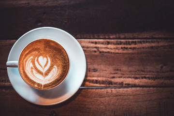 Latte arts coffe. White cup of hot coffee on wooden table. Cafe with barista art concept.