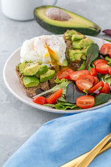 Healthy Breakfast with avocado toasts, poached egg and salad