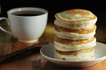 A stack of freshly backed pancakes and a cup of coffee