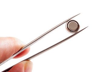 Watch repair and watchmaker replacing the battery concept theme with a hand holding a coin battery in tweezers isolated on white background with a clipping path cutout