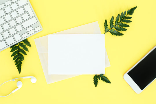 fflatley on yellow background with keyboard, smartphone, headphones and fern leaves, female office, top view, text space, copy space,