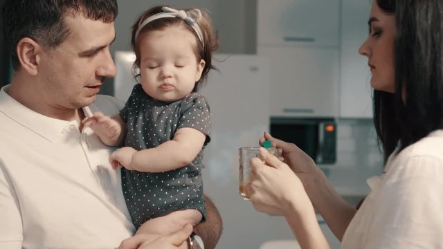Young parents feed baby daughter at home