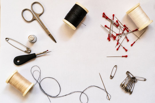 Quick fix sewing kit accessories and tailor equipment for sewing and repairing. Accessories and tools for needlework: scissors, thread spools, needles, pins and safety pins, thimble, flat lay.
