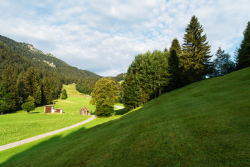 View of the well-groomed alpine meadows with outbuildings and the road stretching into the distance.