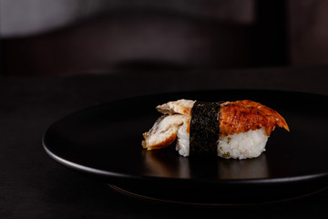 Concept of Asian cuisine. Japanese sushi with soy sauce on a black plate, on a black background. Red Chinese sticks. copy space