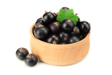 black currant in wooden bowl with green leaf isolated on white background