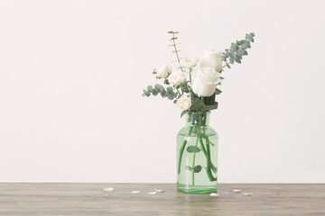eucalyptus twigs and roses  in  glass vase on white background © Maya Kruchancova