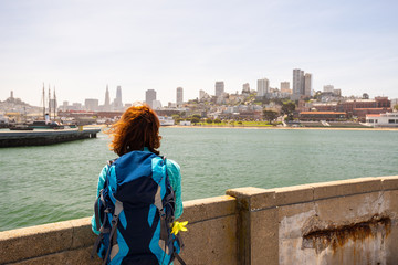 Fototapeta na wymiar Young woman is looking at the San Francisco from a pier in San Francisco, United States of America.