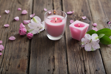 pink candles and flowers on wooden background