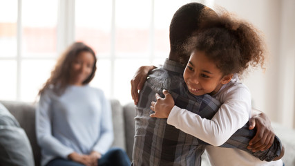 Happy black girl hugging young dad at home