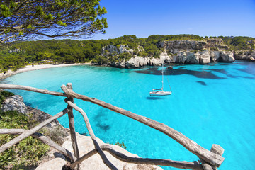 Beautiful Cala Macarella beach, Menorca island, Spain. Sailing boat in a bay. Summer fun, enjoying life, yachting, travel and active lifestyle concept - obrazy, fototapety, plakaty