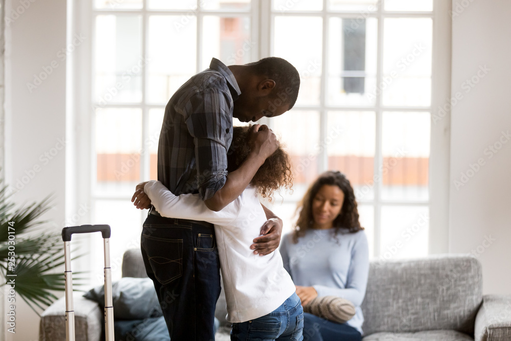 Wall mural sad african american girl hug dad leaving home with suitcase