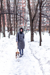 Fototapeta na wymiar Young woman walking in the park with her beagle dog in winter time.