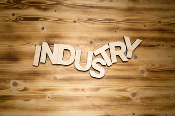 INDUSTRY word made of wooden block letters on wooden board, top view.