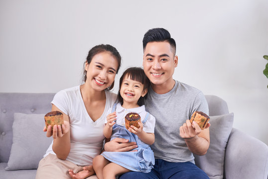 Lively Family Eating Cupcakes In The Living Room At Home