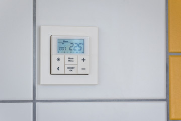 digital heating thermostat showing the temperature on the wall