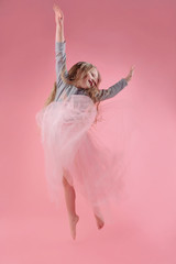 cute funny little girl with long blonde hair jumping on pink background