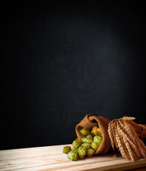Beer, brewery background. Fresh green hop and wheat with wooden barrel on vintage table. Ingredients for brewing. Retro style. Beer brewing traditions. Copy space for your text