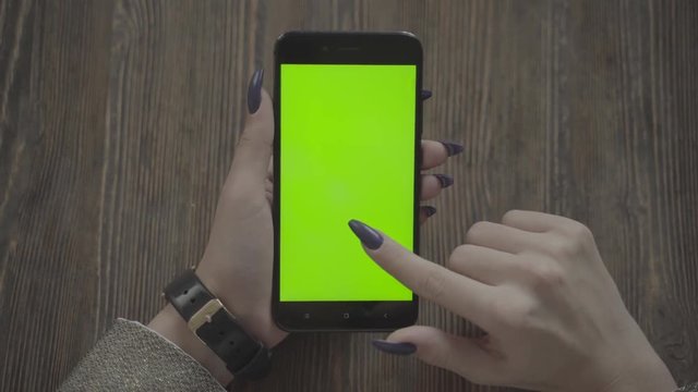 Beautiful girl holding a smartphone in the hands of a green screen green screen.
