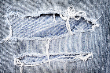 Old blue jeans with ripped texture ,  hole and white threads torn destroyed patterns on denim for background