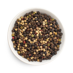 Mix of four types peppercorns in bowl isolated on white background. Top view