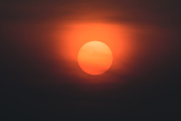 The big red sun is slowly falling, with large black clouds in front.