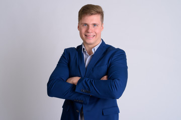 Portrait of young happy blonde businessman smiling with arms crossed