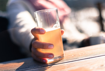 Woman with pink finger polish is drinking a glass of lemonade, outdoors