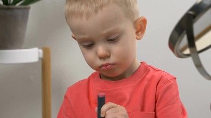 Cute kid playing with mom's cosmetics. Closeup portrait. Beauty, makeup concept