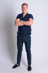 Fototapeta premium Full body shot of young happy handsome man smiling with arms crossed