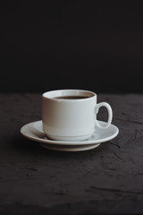 White cup of coffee on a dark background
