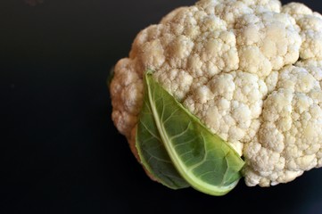 Raw fresh uncooked white cauliflower isolated on black background. Side view, copy text