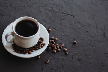 Obraz na płótnie Canvas White cup of coffee and coffee beans on a dark background