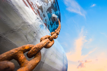 low angle view of Steel anchor chains caked with rust at an industrial port facility, anchor chains roll-in strength with winch motor holding the ship in safe position © ID_Anuphon