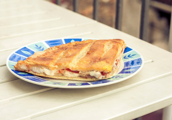 Fried calzone pizza with ham, mozzarella, tomatoes from bakery shop of Catania, Sicily, Italy.