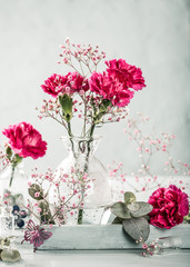 Bouquet of pink carnation flowers in glass vase on light turquoise wooden background. Mothers day, birthday greeting card. Copy space. Toned.