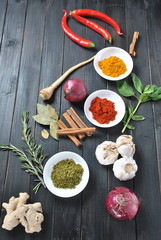 Colorful various of fresh and dried herbs, spices for cooking. Spice and herb seasoning, paprika powder, cinnamon, red onion. garlic, basil, ginger root on dark background