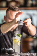 Professional barman making  alcoholic cocktail drink with fruits sugar and herbs