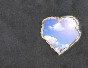 Blue sky with clouds and bright sun in a hole paper
