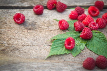 a scattering of raspberry and raspberry leaves on a wooden background