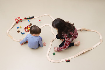 Geschwister spielen mit einer Holzeisenbahn